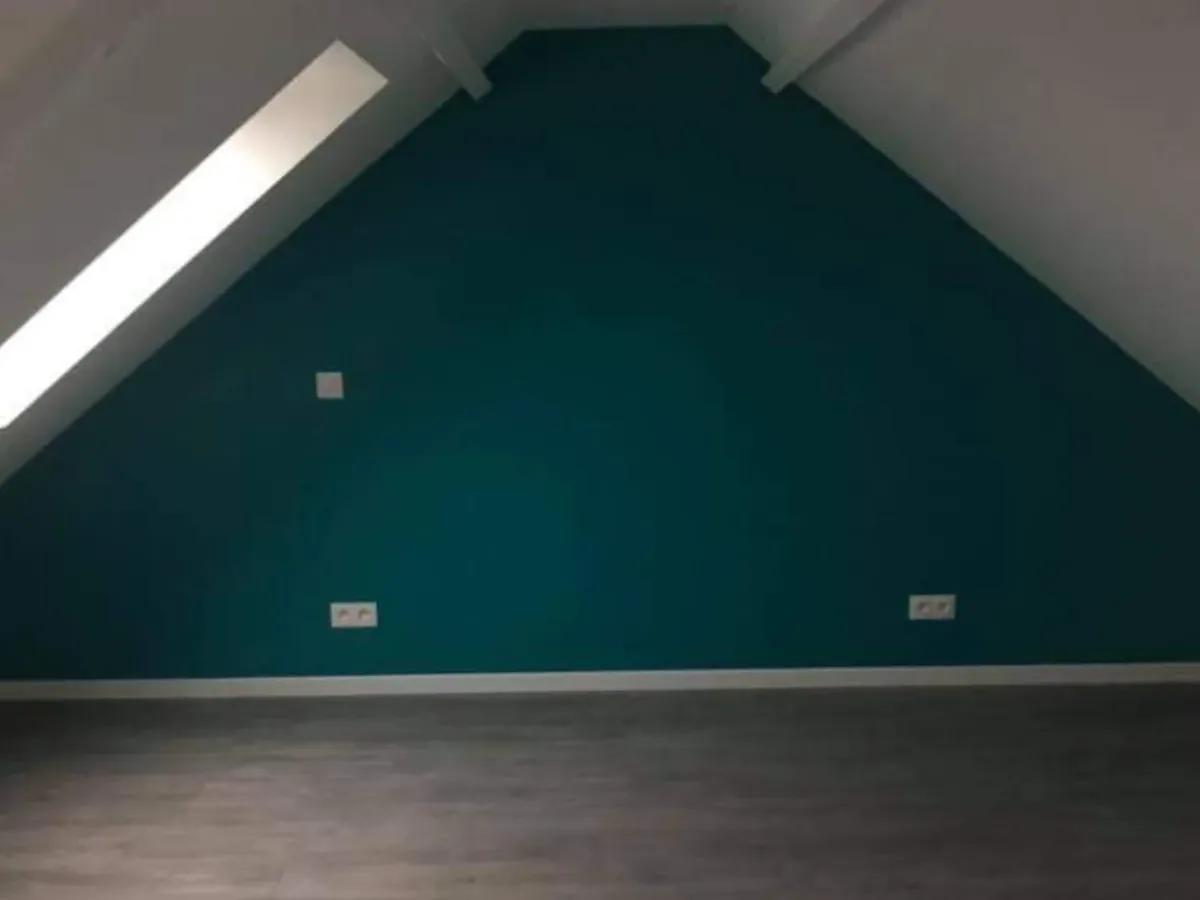 Mur peint dans un vert profond sous rampant, sol stratifié posé par ATM