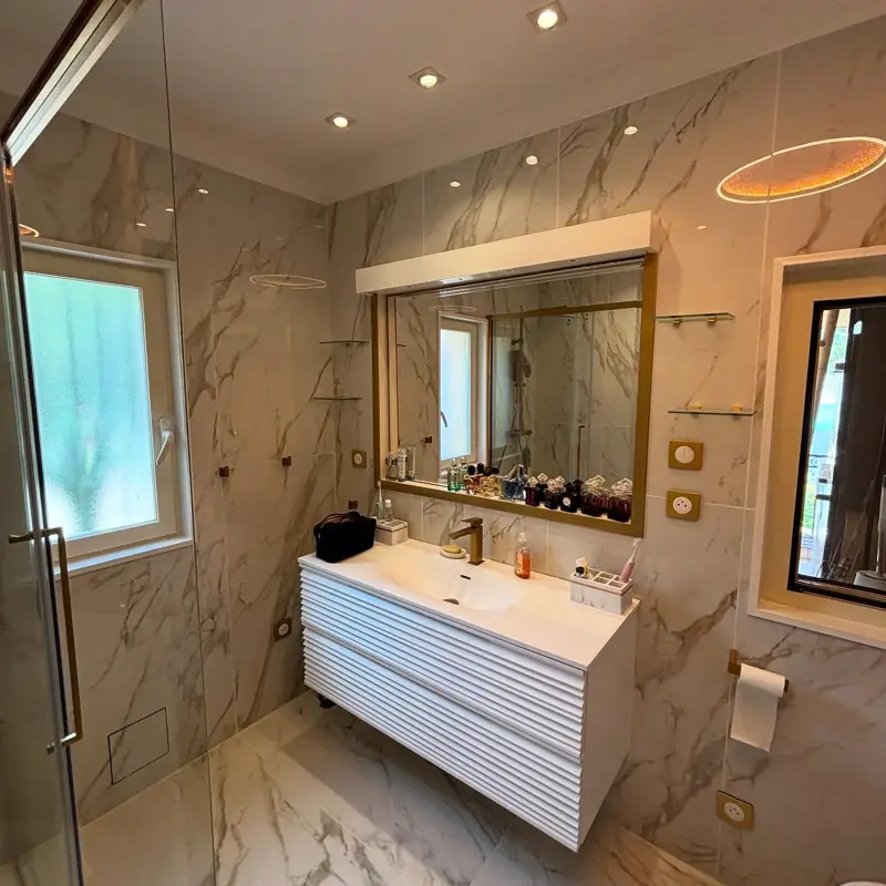 Salle de bains rénovée par ATM, carrelage effet marbre et robinetterie laiton